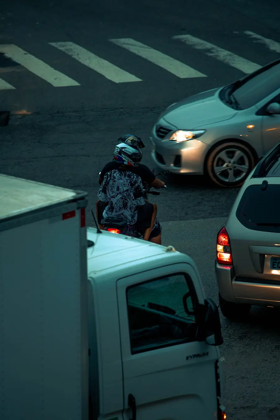 Vista de cima de motociclista passando entre carros no trânsito